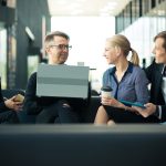 Business team sitting in office lobby with laptop and talking